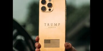 نمای پشت گوشی هوشمند با بدنه طلایی براق، لوگوی متنی TRUMP MOBILE در مرکز، ماژول دوربین مربعی با چهار دهانه لنز در گوشه بالا و نماد پرچم ایالات متحده در بخش پایینی بدنه