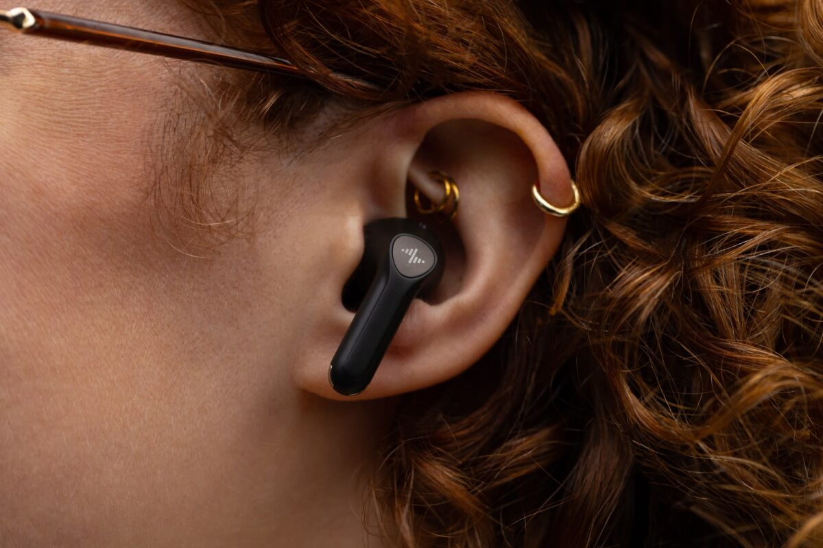 هدفونهای بیسیم Subtle Voicebuds در کنار گوشی آیفون که در حال نمایش رابط کاربری چت هوش مصنوعی و ضبط صدا است.