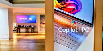 استند تبلیغاتی در یک فروشگاه که لپ‌تاپی با عنوان "Copilot+ PC" را نمایش می‌دهد.