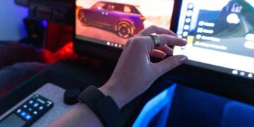 نمای داخلی کابین خودرو با نمایشگرهای دیجیتال داشبورد؛ دست دارای مچ‌بند هوشمند Garmin در حال تعامل با رابط کاربری سیستم اطلاعات‌سرگرمی، نمایش منوها و گزینه‌های کنترلی روی صفحه