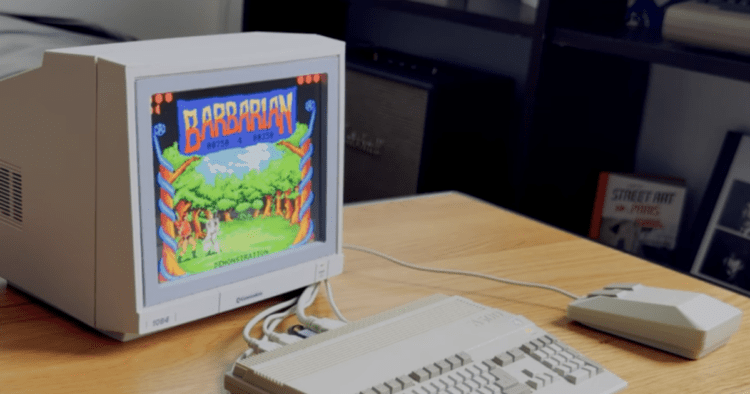 رایانه کلاسیک Commodore مجهز به مانیتور CRT روی میز چوبی، در حال اجرای بازی رترو Barbarian با نمایش گرافیک پیکسلی رنگی، به همراه صفحه‌کلید و ماوس کلاسیک