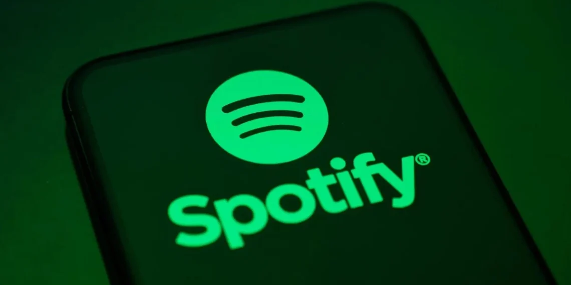 لوگوی Spotify با نماد دایره‌ای سبزرنگ و خطوط صوتی، نمایش‌داده‌شده روی صفحه یک گوشی هوشمند با پس‌زمینه تیره، که هویت بصری سرویس استریم موسیقی اسپاتیفای را برجسته می‌کند.
