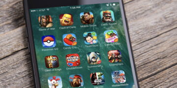 نمای نزدیک از صفحه یک گوشی هوشمند که مجموعه‌ای از آیکن بازی‌های موبایلی محبوب مانند Pokémon GO، Clash of Clans، Candy Crush، Hay Day و Madden Mobile را در قالب یک پوشه روی صفحه‌نمایش نشان می‌دهد.