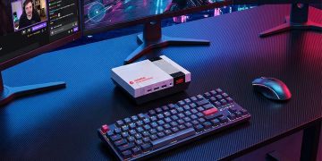 نمای یک میز کار با کیبورد مکانیکی و مینی پی‌سی Acemagic Retro X5 با طراحی کلاسیک شبیه به کنسول‌های قدیمی در مرکز میز.