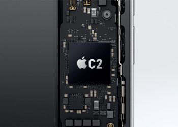 نمای داخلی یک گوشی هوشمند با تمرکز بر برد الکترونیکی و چیپ Apple C2 که به‌عنوان مودم 5G اختصاصی اپل روی مادربورد نصب شده است؛ لوگوی اپل و نام C2 روی تراشه دیده می‌شود و اطراف آن با قطعات ریز الکترونیکی احاطه شده که نشان‌دهنده یکپارچگی سخت‌افزاری و توسعه فناوری ارتباطی داخلی اپل است.