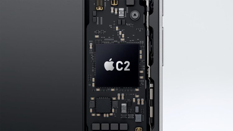 نمای داخلی یک گوشی هوشمند با تمرکز بر برد الکترونیکی و چیپ Apple C2 که بهعنوان مودم 5G اختصاصی اپل روی مادربورد نصب شده است؛ لوگوی اپل و نام C2 روی تراشه دیده میشود و اطراف آن با قطعات ریز الکترونیکی احاطه شده که نشاندهنده یکپارچگی سختافزاری و توسعه فناوری ارتباطی داخلی اپل است.