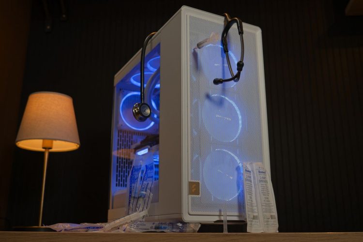 یک کیس کامپیوتر سفید با نورپردازی آبی که با وسایل پزشکی مثل گوشی طبی و سرنگ تزیین شده است.