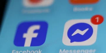 نمای نزدیک از آیکونهای آبی رنگ فیسبوک و ماسنجر روی صفحه نمایش یک گوشی هوشمند.