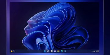 تصویر پس‌زمینه پیش‌فرض ویندوز ۱۱ (Bloom) به رنگ آبی تیره بر روی یک مانیتور.