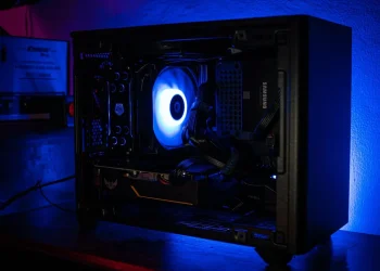 نمای داخلی یک کیس کامپیوتر گیمینگ با نورپردازی آبی و فن خنک‌کننده در حال چرخش.