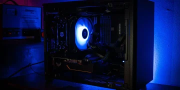 نمای داخلی یک کیس کامپیوتر گیمینگ با نورپردازی آبی و فن خنک‌کننده در حال چرخش.