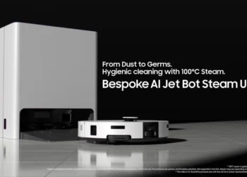 ربات جاروبرقی هوشمند Samsung Bespoke AI Jet Bot Steam Ultra در حال شارژ کنار ایستگاه اصلی، با متن تبلیغاتی «From Dust to Germs – Hygienic cleaning with 100°C Steam» و طراحی مینیمال سفید و مشکی روی کف سرامیکی.
