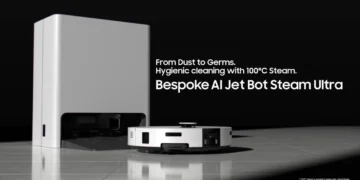 ربات جاروبرقی هوشمند Samsung Bespoke AI Jet Bot Steam Ultra در حال شارژ کنار ایستگاه اصلی، با متن تبلیغاتی «From Dust to Germs – Hygienic cleaning with 100°C Steam» و طراحی مینیمال سفید و مشکی روی کف سرامیکی.
