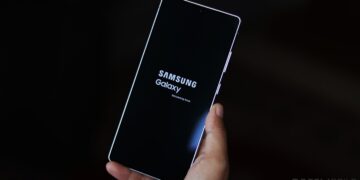 گوشی سامسونگ در دست که در حال بوت شدن است و لوگوی "Samsung Galaxy Secured by Knox" را نشان می‌دهد.