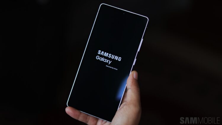 گوشی سامسونگ در دست که در حال بوت شدن است و لوگوی "Samsung Galaxy Secured by Knox" را نشان می‌دهد.