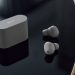 هدفون بی‌سیم Sony XM6 به رنگ نقره‌ای در کنار کیس شارژ روی میز براق.