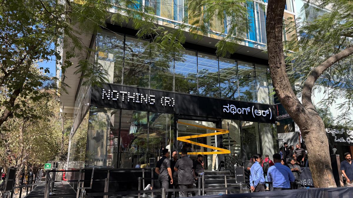 نمای بیرونی فروشگاه رسمی Nothing ® در هند، با معماری مدرن شیشهای و لوگوی LED برند Nothing روی نمای ساختمان. طراحی مینیمال فروشگاه با ورودی پلکانی، المانهای صنعتی و فضای شهری اطراف، هویت بصری متمایز برند را برجسته میکند.