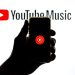 ضد نور دستی که یک گوشی هوشمند با لوگوی یوتیوب را در مقابل پس‌زمینه درخشان "YouTube Music" نگه داشته است.