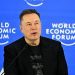 نمای یک سخنرانی رسمی در رویداد World Economic Forum با پس‌زمینه آبی و لوگوی تکرارشونده این رویداد جهانی. یک سخنران با پوشش رسمی در پشت تریبون و میکروفن قرار دارد و فضای تصویر، حال‌وهوای کنفرانس اقتصادی بین‌المللی، سیاست‌گذاری و فناوری را منتقل می‌کند.