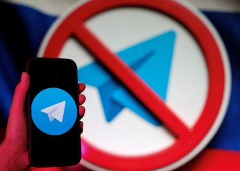 تصویر مفهومی از اپلیکیشن پیامرسان Telegram که روی صفحه یک گوشی هوشمند نمایش داده شده و در پسزمینه، نماد ممنوعیت (Prohibition Sign) روی لوگوی تلگرام دیده میشود. این تصویر به محدودسازی، فیلترینگ یا مسدودسازی تلگرام در یک کشور و چالشهای دسترسی به پیامرسانها اشاره دارد.