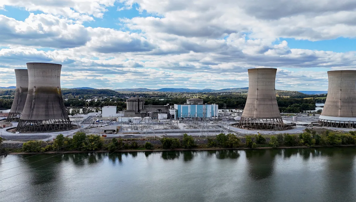 نمای پانورامای یک نیروگاه بزرگ با برجهای خنککننده صنعتی در کنار رودخانه، با تأسیسات انرژی و چشمانداز طبیعی در پسزمینه