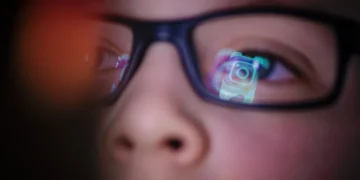 تصویر مفهومی با تمرکز بر بازتاب رابط کاربری اینستاگرام و رنگ‌های نئونی که تعامل کاربر نوجوان با شبکه اجتماعی را به صورت نمادین نشان می‌دهد