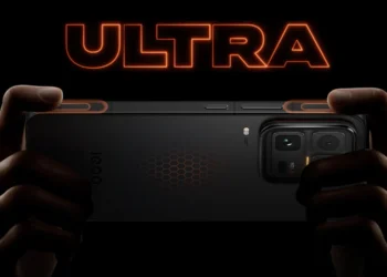 نمای پشت گوشی iQOO 15 Ultra با طراحی مشکی مات، ماژول دوربین بزرگ چندگانه و الگوی شش‌ضلعی روی بدنه، در پس‌زمینه‌ای نارنجی با حال‌و‌هوای آینده‌نگرانه و نوشته ULTRA 2077.