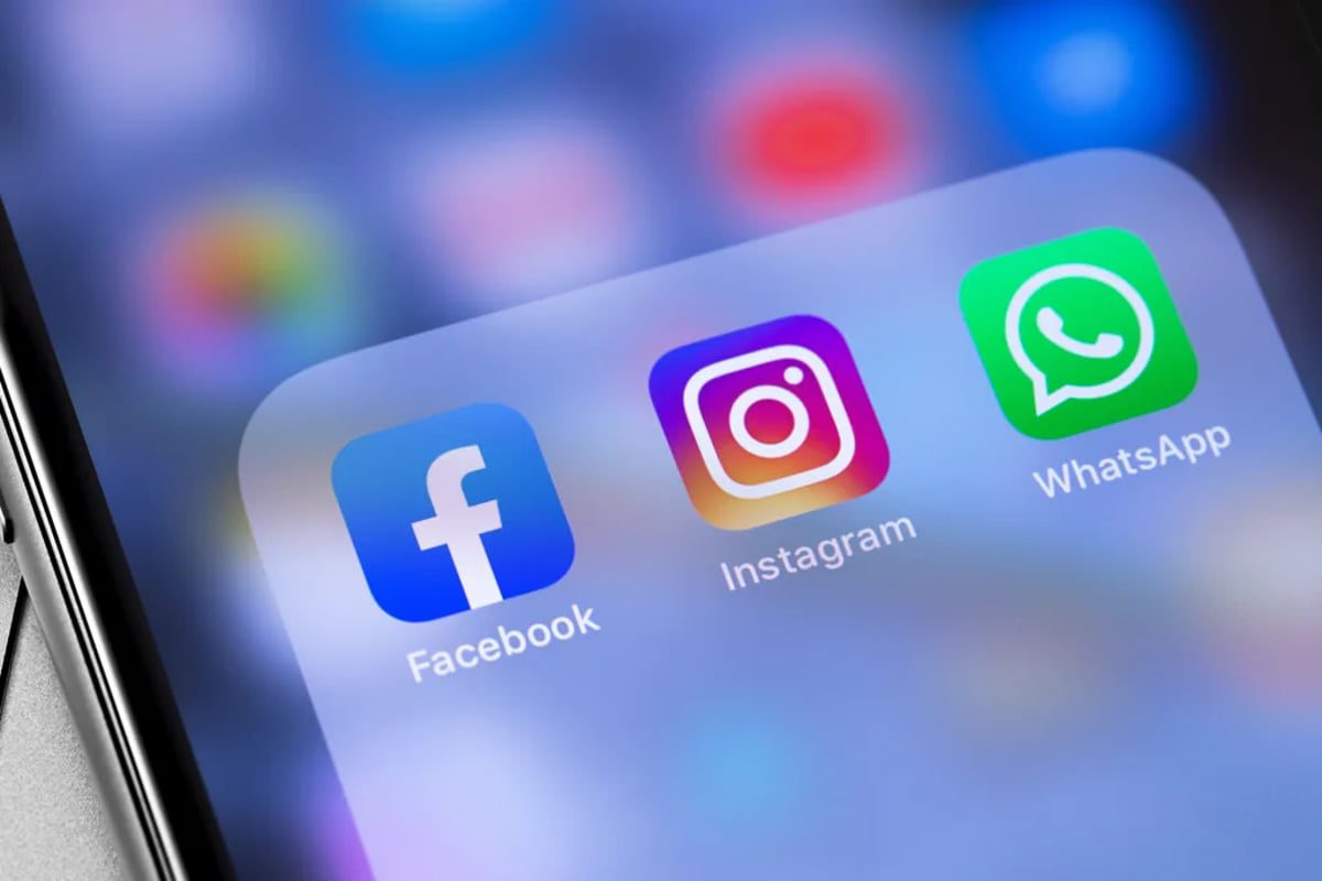 نمای نزدیک از یک گوشی هوشمند با سه آیکون برنامه‌های Facebook، Instagram و WhatsApp در صفحه اصلی، با پس‌زمینه گرادینت آبی–بنفش و فوکوس روی بخش اپلیکیشن‌ها. این تصویر نماد ارتباط متقابل سرویس‌های اصلی Meta در زمینه آزمایش طرح اشتراک پولی (Paid Subscription) برای پلتفرم‌هاست.