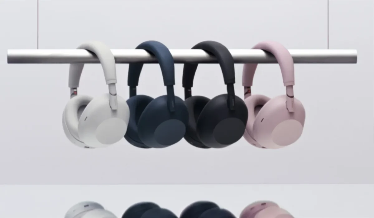 چهار هدفون Sony WH‑1000XM6 آویزان از میله فلزی در رنگهای سفید، آبی تیره، مشکی و Sand Pink که تنوع رنگبندی سری 1000X و طراحی یکپارچه ایرکاپها و هدبند را نمایش میدهد.