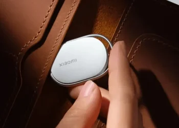 نمایی نزدیک از یک ردیاب هوشمند سفید شیائومی که از لبه یک کیف چرمی قهوه‌ای بیرون زده است.