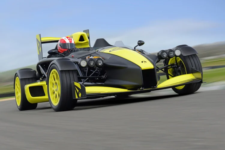 نمای جلو و در حال حرکت خودروی Ariel Atom 4RR با بدنه مشکی و زرد در پیست مسابقه.