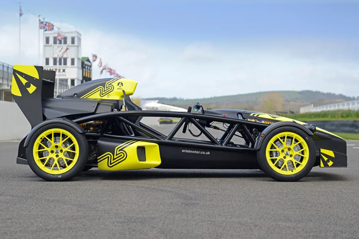 نمای جانبی کامل Ariel Atom 4RR با شاسی لوله‌ای و رینگ‌های زرد رنگ در فضای باز.