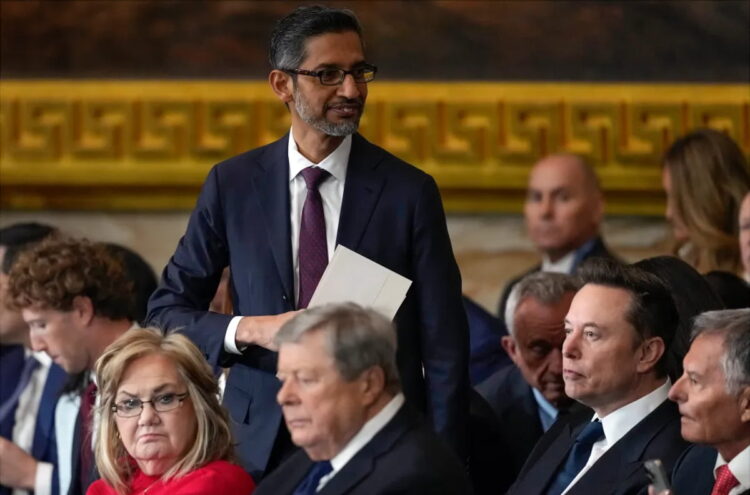 حضور گروهی از افراد در یک مراسم رسمی؛ رییس گوگل Sundar Pichai با کتوشلوار تیره و کراوات ایستاده و پوشهای در دست دارد، درحالیکه سایر شرکتکنندگان روی صندلیها نشستهاند