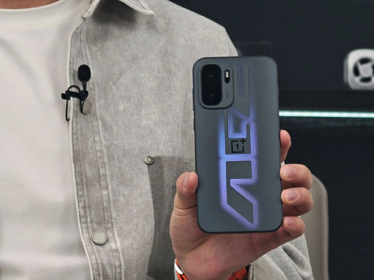 فردی گوشی OnePlus با قاب تیره و الگوی نورانی بنفش درخشان را در دست گرفته است؛ ماژول دوربین مستطیلی و لوگوی OnePlus در مرکز قاب دیده میشود