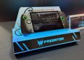 کنسول دستی گیمینگ Acer Predator Atlas 8 روی استند نمایشگاهی با نور آبی، با نمایش یک بازی مسابقهای روی صفحه و دکمهها و جویاستیکهای دو طرف