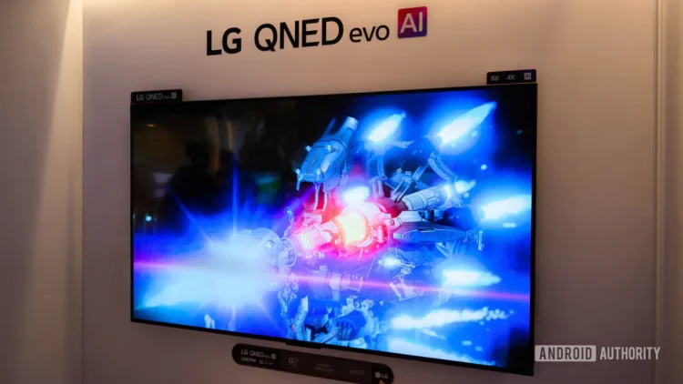 تلویزیون بزرگ LG QNED evo AI روی دیوار نمایشگاهی که صحنه‌ای علمی‌تخیلی با نورهای آبی و قرمز را نمایش می‌دهد؛ واترمارک Android Authority در گوشه تصویر دیده می‌شود