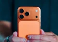 گوشی iPhone 17 Pro در رنگ نارنجی با ماژول دوربین بزرگ مستطیلی و سه لنز در گوشه بالا، روی پسزمینهای ساده و روشن.