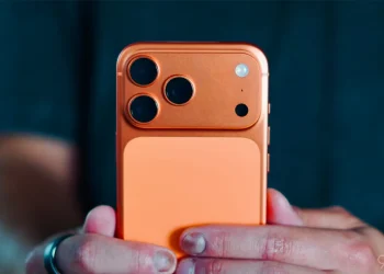 گوشی iPhone 17 Pro در رنگ نارنجی با ماژول دوربین بزرگ مستطیلی و سه لنز در گوشه بالا، روی پس‌زمینه‌ای ساده و روشن.