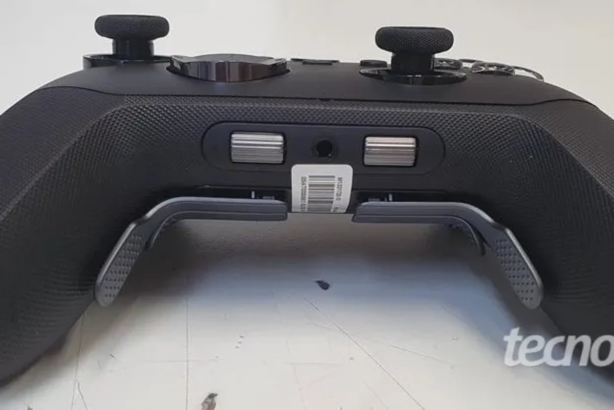 تصویر بخش زیرین کنترلر Xbox Elite Series 3 را از زاویه نزدیک نشان می‌دهد. دو پدال فلزی بزرگ در پایین هر طرف قرار دارند. در مرکز درگاه شارژ و کنار آن دو دکمه نقره‌ای کوچک به چشم می‌خورند. برچسب بارکد در وسط لبه پایینی دیده می‌شود.