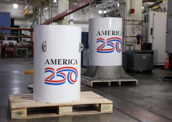 کپسول زمان پروژه America250 با بدنه فلزی سفید در مرکز صنعتی، پیش از دفن برای ۲۵۰ سال آینده آماده‌سازی می‌شود.