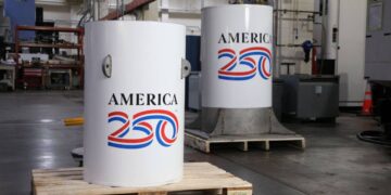 کپسول زمان پروژه America250 با بدنه فلزی سفید در مرکز صنعتی، پیش از دفن برای ۲۵۰ سال آینده آماده‌سازی می‌شود.