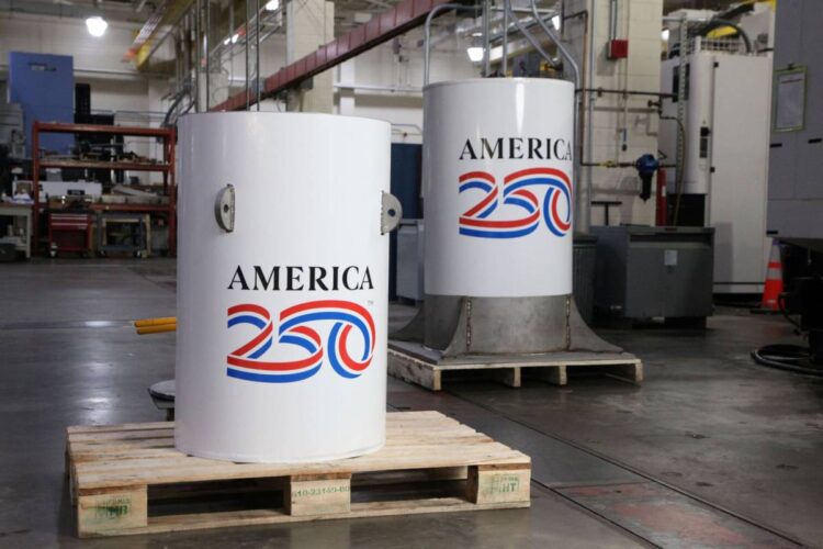 کپسول زمان پروژه America250 با بدنه فلزی سفید در مرکز صنعتی، پیش از دفن برای ۲۵۰ سال آینده آمادهسازی میشود.