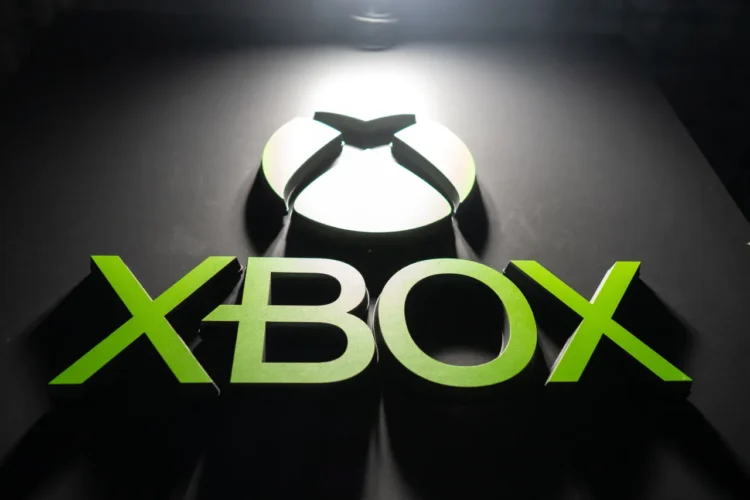 لوگوی XBOX با رنگ سبز درخشان؛ حرف X شکل بازی، به همراه نوشته XBOX که با نورپردازی از بالا روی سطح مشکی برجسته شده است