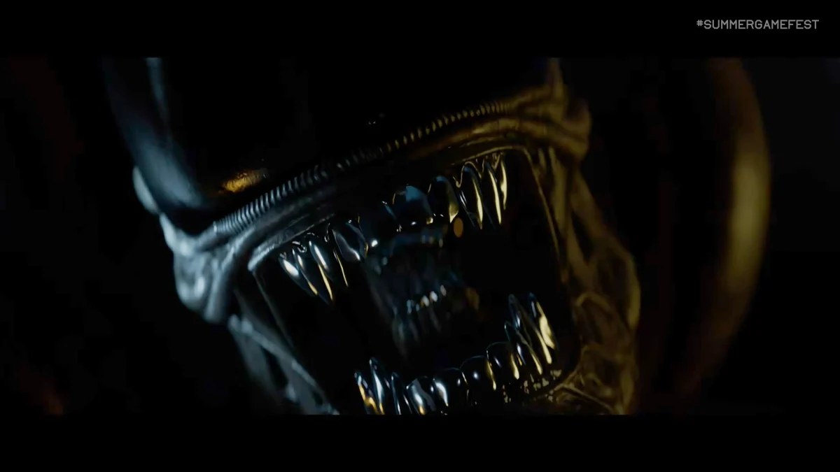 نمای بسیار نزدیک و ترسناک از دهان باز و دندانهای فلزی درخشان یک موجود Alien (زنومورف) در تاریکی با هشتگ Summer Game Fest