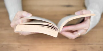 مقایسه کتاب کاغذی و لپ‌تاپ در یک تصویر مفهومی؛ نمایش تفاوت مطالعه روی کاغذ و نمایشگرهای دیجیتال