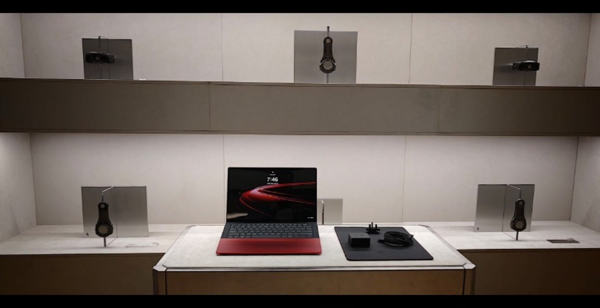 لپ‌تاپ HP Spectre نسخه فراری روی میز نمایشگاه در کنار قطعات مکانیکی موتور خودرو که روی دیوار نصب شده‌اند