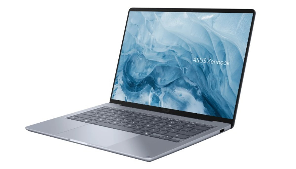 نمای سهرخ از لپتاپ جدید ایسوس ذنبوک (ASUS Zenbook) با بدنه باریک نقرهای؛ نمایشگر با والپیپر انتزاعی آبیرنگ و نوشته ASUS Zenbook روی صفحه