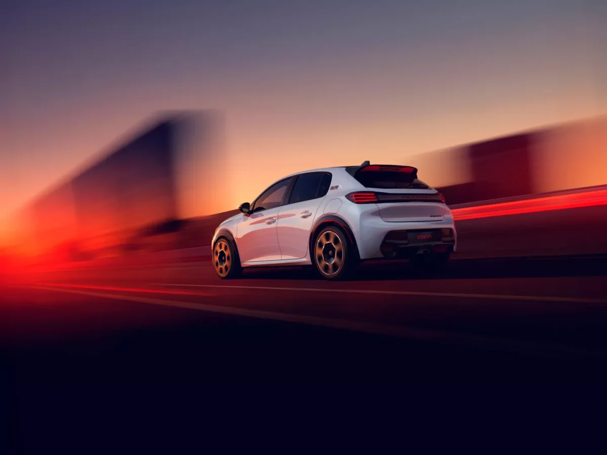 نمای عقب و سهربع پژو E-208 GTi با اسپویلر سقفی، رینگهای اسپرت و پسزمینه نورانی هنگام حرکت