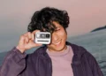 کاربری در فضای ساحلی، دوربین Polaroid Go Generation 3 را مقابل صورت خود گرفته و قابلیت حمل آسان و ابعاد کوچک آن را به نمایش میگذارد.