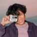 کاربری در فضای ساحلی، دوربین Polaroid Go Generation 3 را مقابل صورت خود گرفته و قابلیت حمل آسان و ابعاد کوچک آن را به نمایش میگذارد.